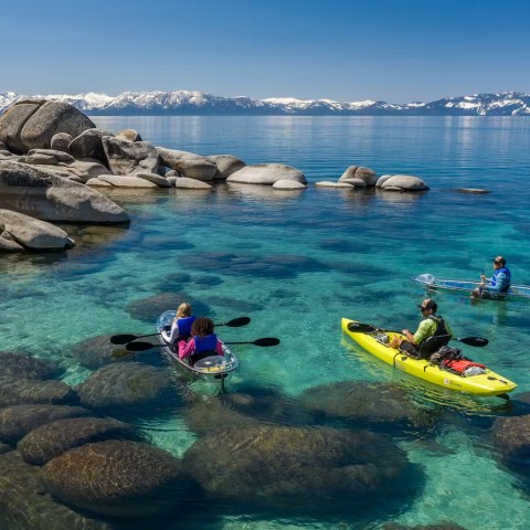 a group of people sitting on a rock next to a body of water